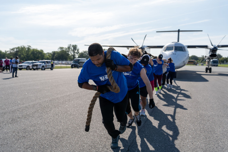Group of people using a rope to pull an airplane