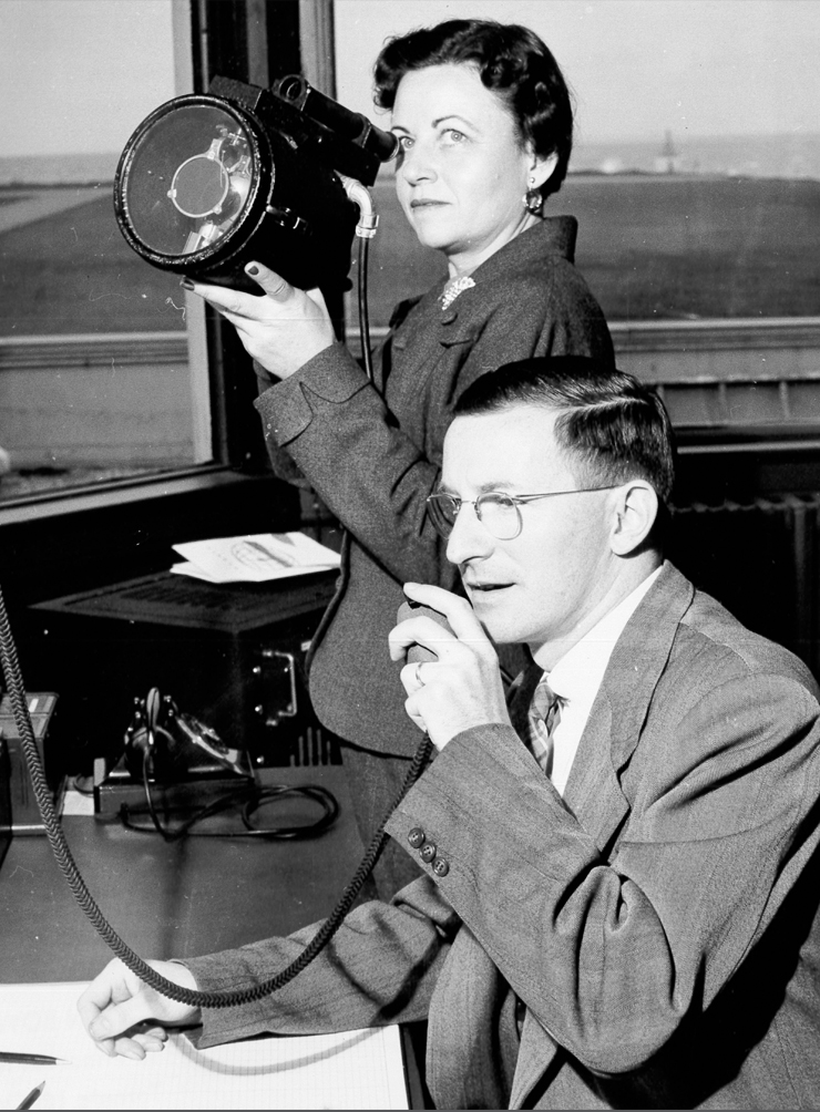 Man on radio with lady in background with air traffic control light