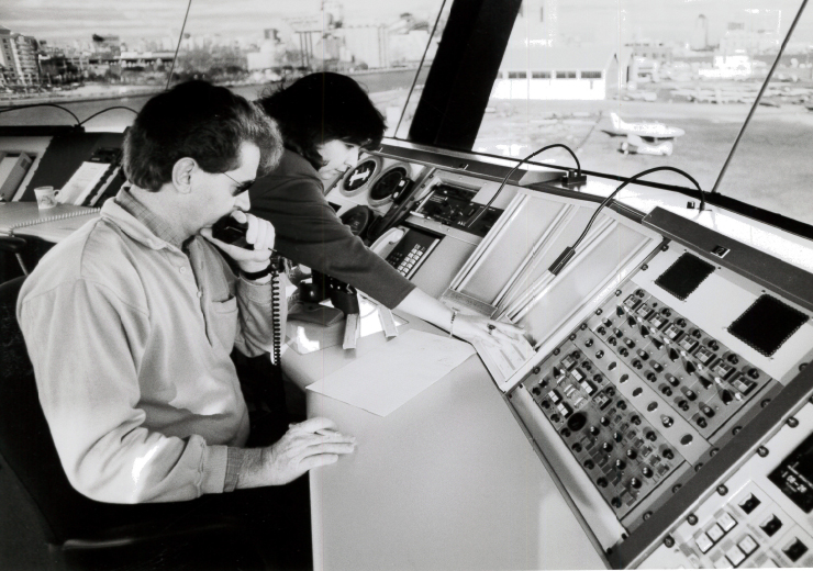 Meteorologists infront of complex panel of switches