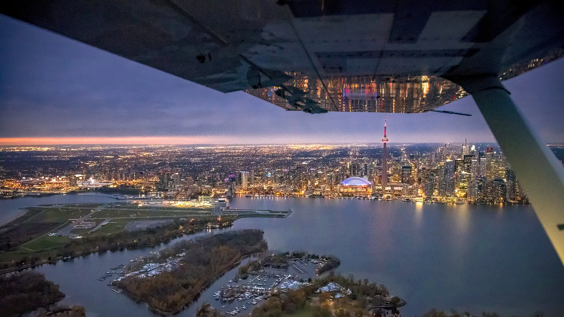 Night time aerial shot of downtown Toronto, the airport and lake Ontario