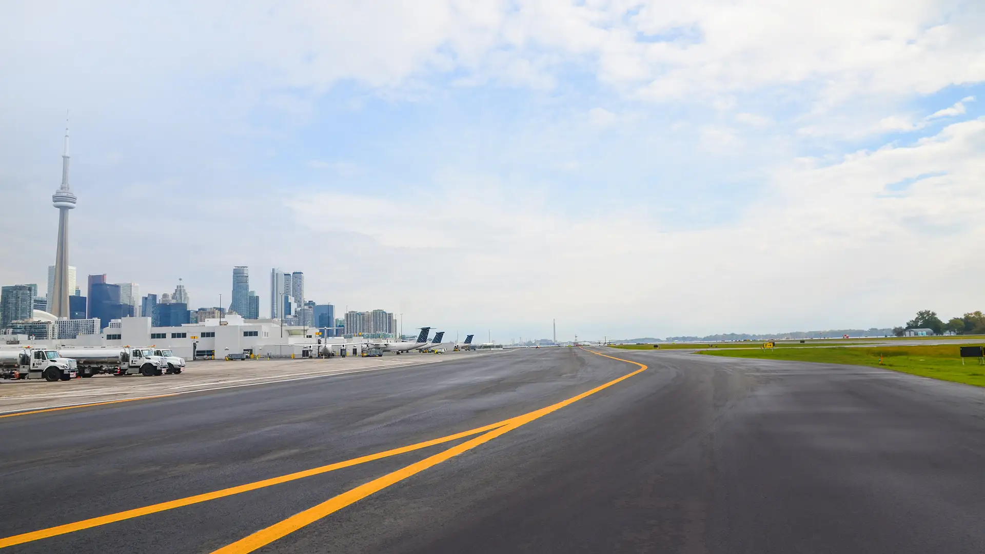 Photo centered on the Billy Bishop Toronto City Airport runway with planes and the Toronto skyline in the background