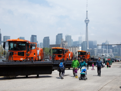 Families walk near airport maintenance vehicles on display as part of Doors Open at Billy Bishop Toronto City Airport.