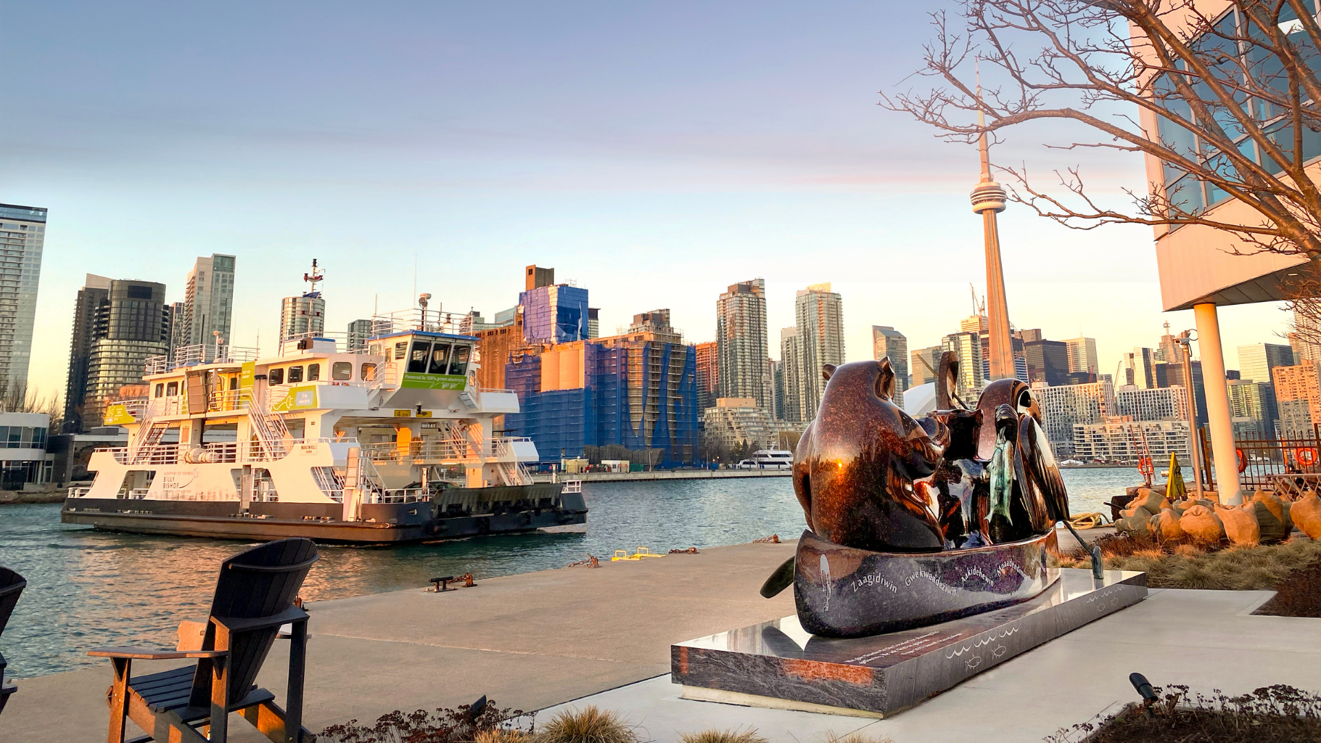 granite sculpture overlooking the water with ferry and city skyline in the bcakground