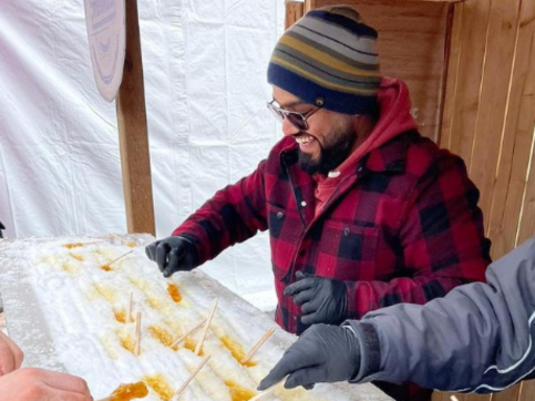 Person dressed for winter enjoying maple candy