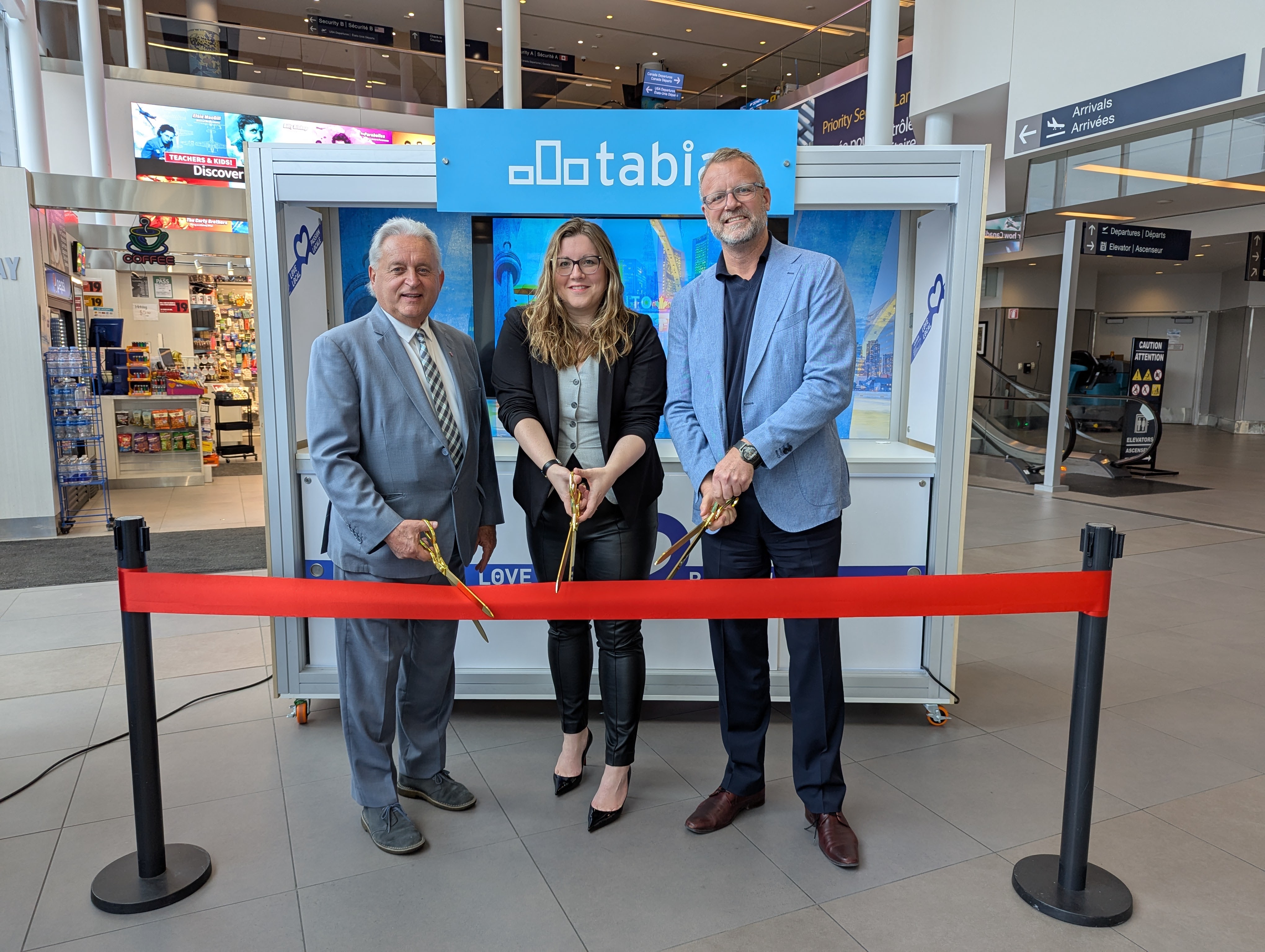 Ribbon cutting beside a TABIA display inside the airport terminal.