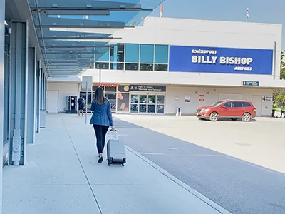 A traveller with a suitcase approaches Billy Bishop Airport’s mainland entrance.