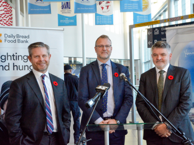 Speakers beside a Daily Bread Food Bank display in the airport atrium.