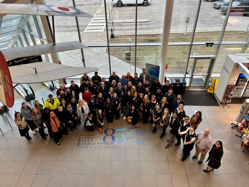 A group gathers in the airport atrium for its 85th anniversary.